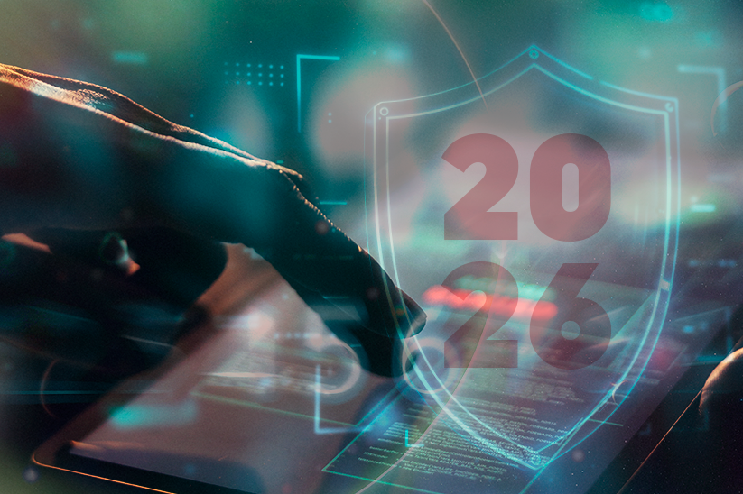 Imagem de uma mão teclado em um computador sobre posta pela imagem de um escudo com a escrita 2026